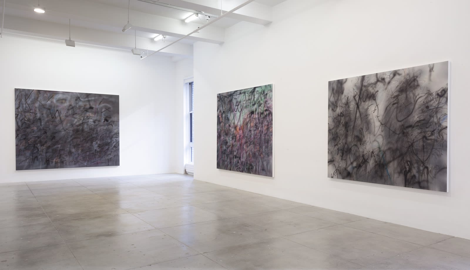 3 abstract paintings hang in a white gallery space with a window.