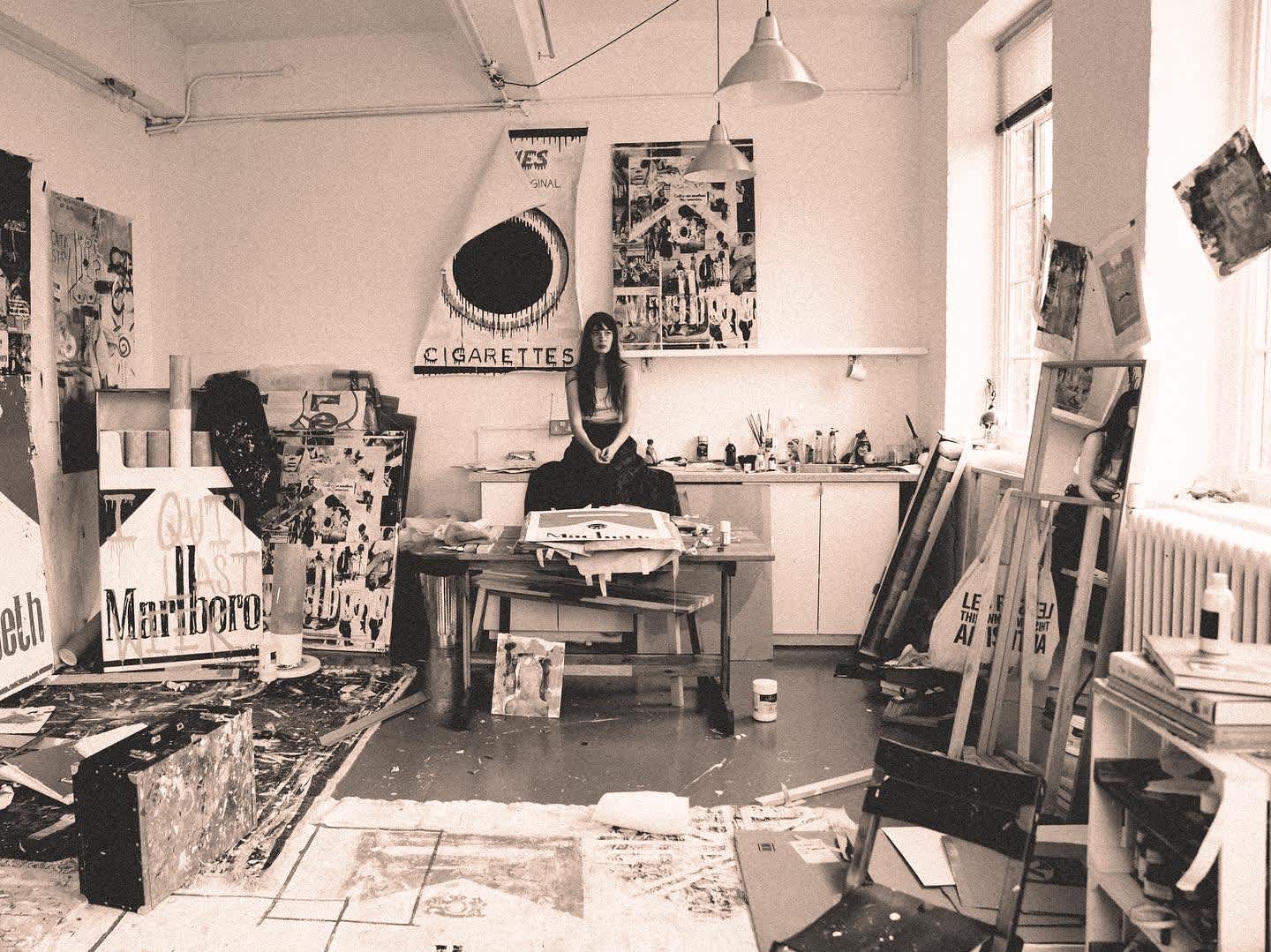 The Charlotte Rose art studio is filled with Pop art artworks to completion, with the model sitting between her creations.