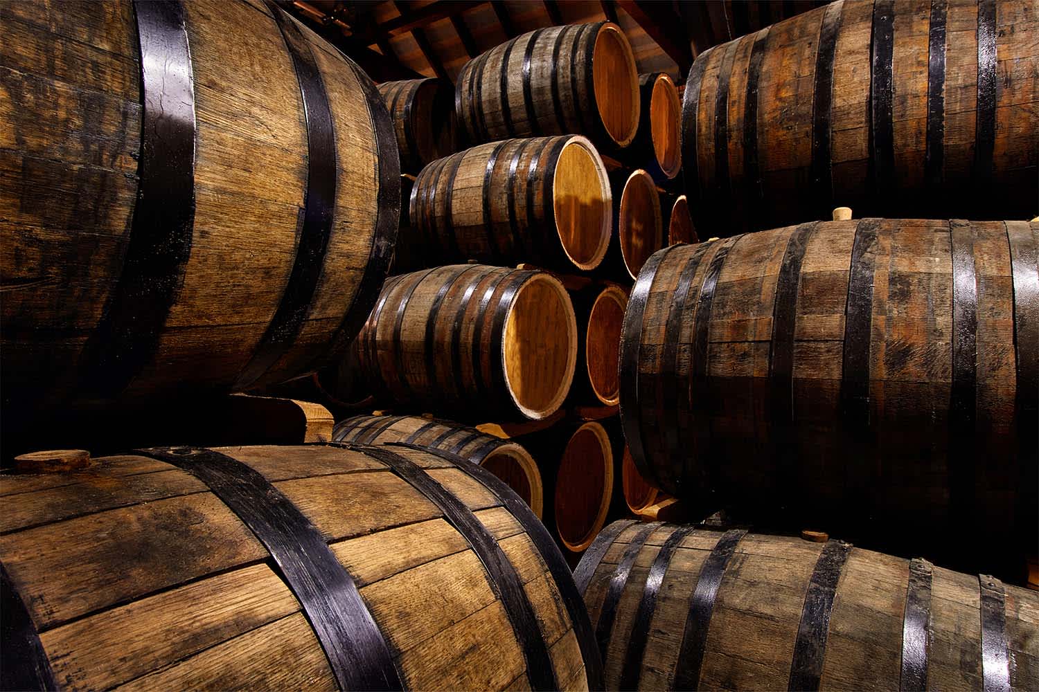 Wooden barrels are stacked in a cellar; passion assets owned by investors who have diversified their portfolios with whiskey cask investment.