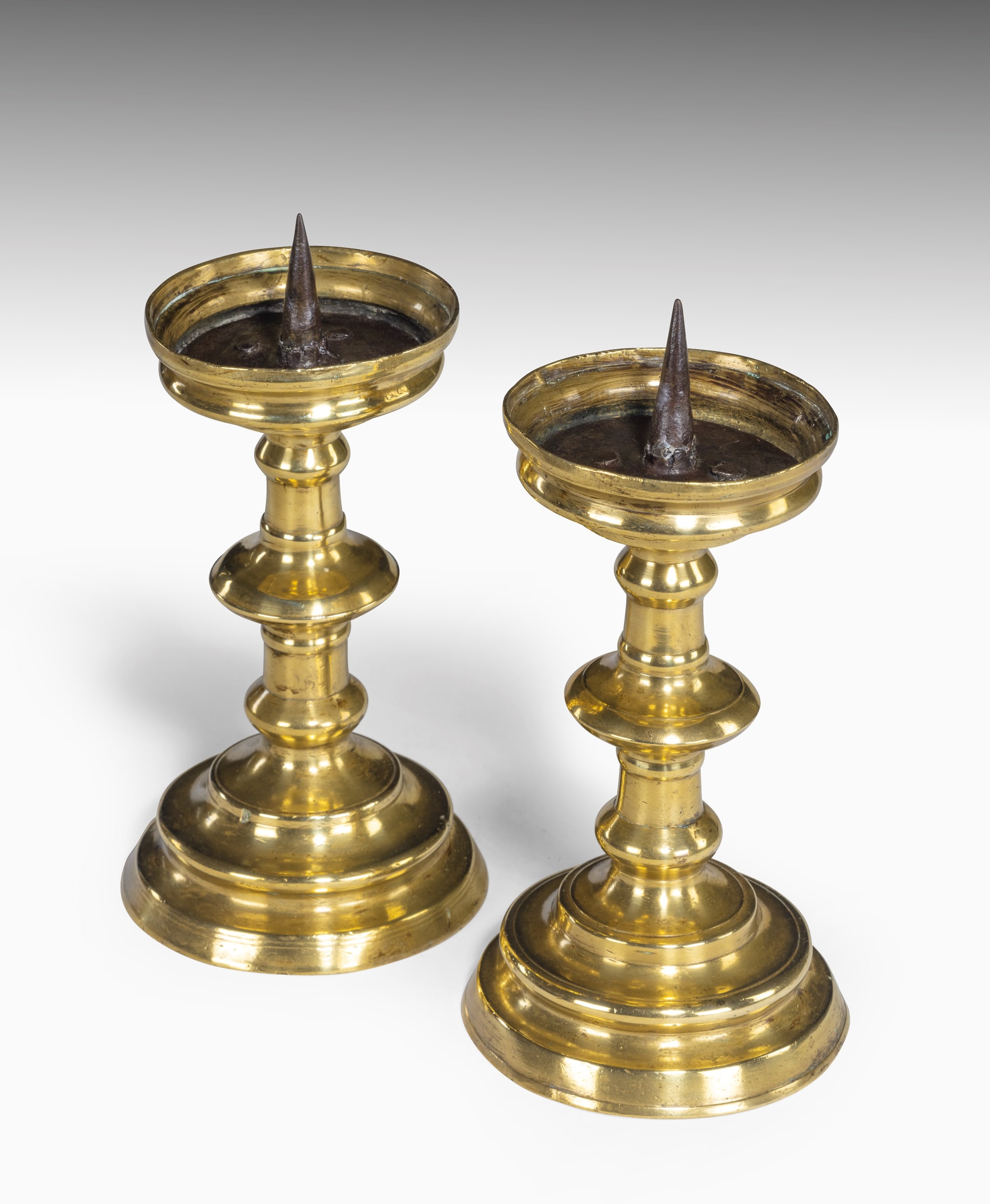 Lot - Two pair brass pricket sticks, details include: smaller made of brass  and with scroll and shell motif, raised on three paw feet, no