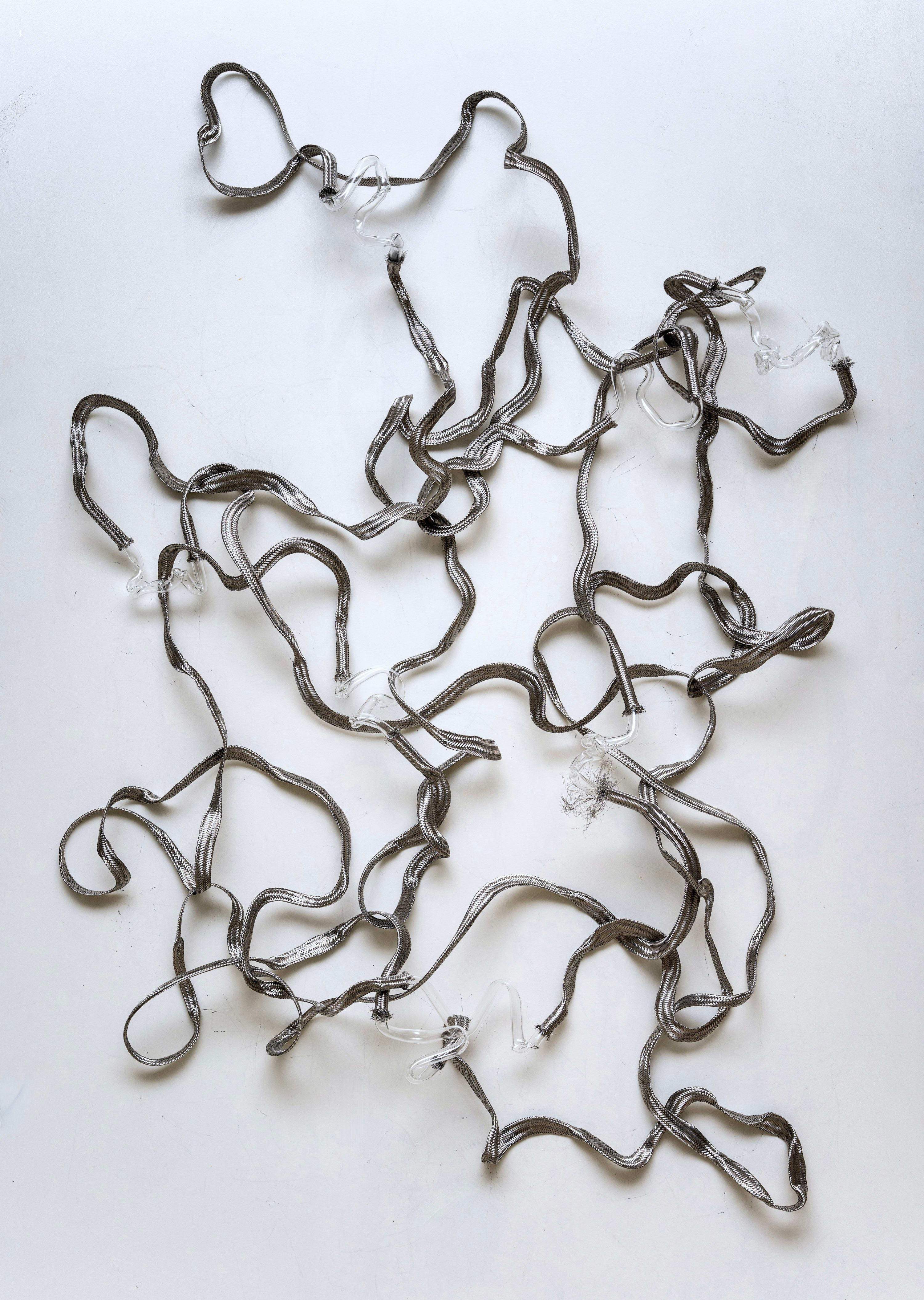 In Finding Flow, two opposing materials -metal and glass- are brought into a state of suspended tension. Hand-shaped glass forms...