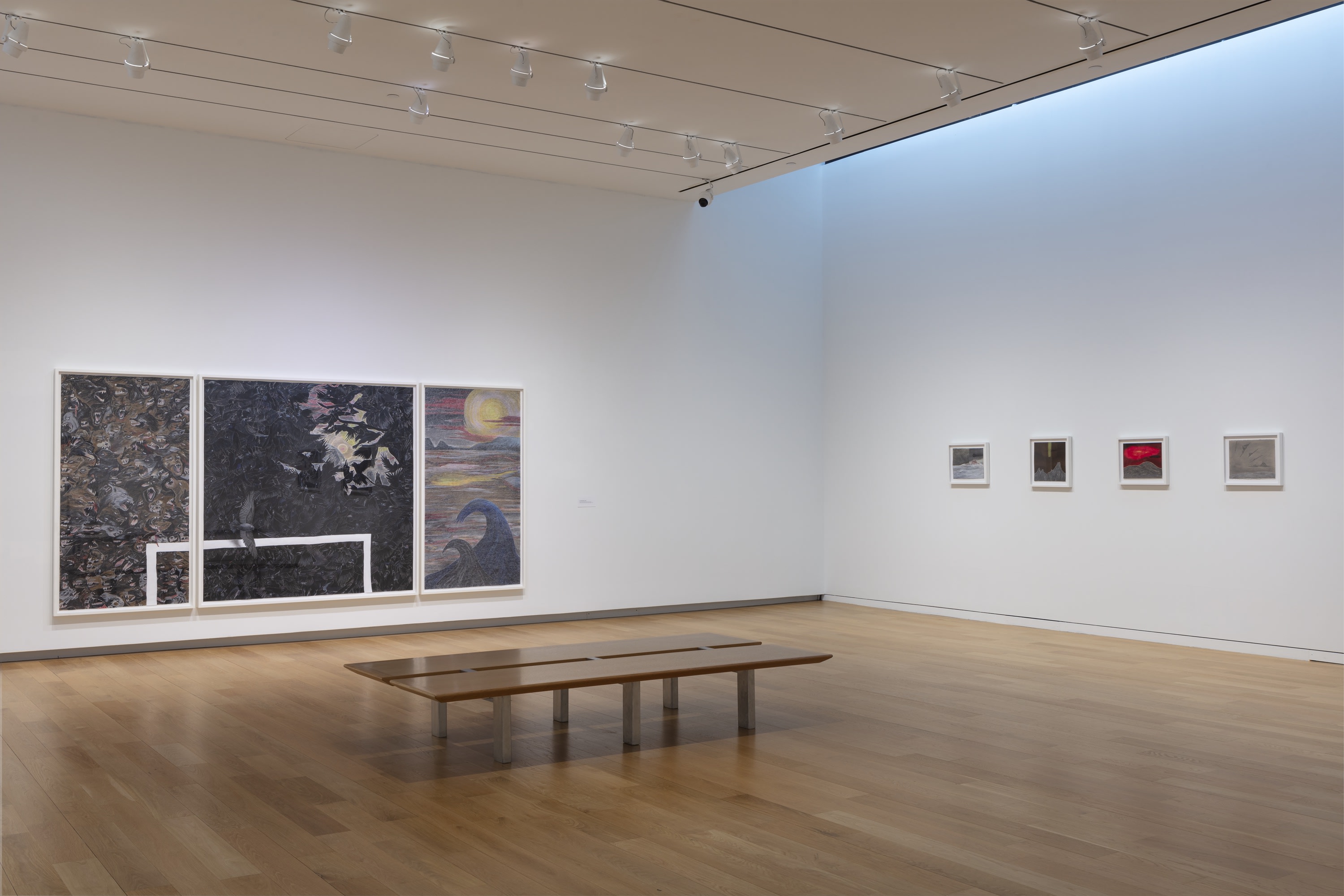 Installation view of Robyn O'Neil: WE THE MASSES at the Modern Museum of Art in Fort Worth Texas, with a large triptych on one wall and several smaller drawings on the other and a bench in the center of the room