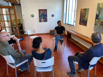 People sitting in a circle listening to an artist give a talk