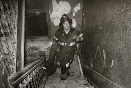 Jill Freedman, Untitled [A firefighter carries the fire hose nozzle upstairs in an apartment block in the South Bronx, New York City], circa 1976