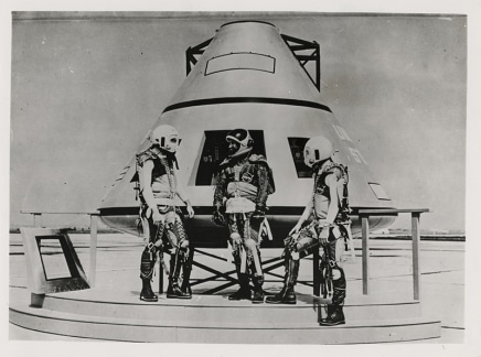 Photographer Unknown, [Three American astronauts in space suits in front of a replica space capsule], August 10, 1962
