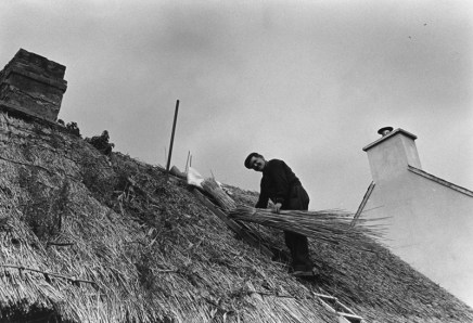 Jill Freedman, Untitled [Man fixing thatched roof], circa 1985