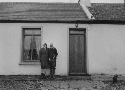 Jill Freedman, Untitled [Irish couple in front of house with fiddle], circa 1985