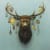 a mounted deer head with different ornaments hanging from its antlers