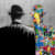 black and white image of the back of a man wearing a bowler hat. A reflection of the man is in front of him made from graffiti