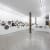 installation image of white walls with round paintings hung salon style