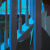 painting by artist Adrian Kay Wong depicting an individual sitting in a blue stairwell, beyond the stairs is a fish tank with orange fish, a small bonsai tree, and a small jade necklace hanging from the banister