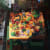Painting of a kitchen island with various foods, drinks and cooking utensils surrounded by a kitchen