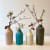 Linda Bloomfield range of ceramic bottles stood in line next to one another, steams of blossom occupy them