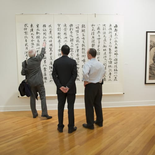 A group of men looking at a painting