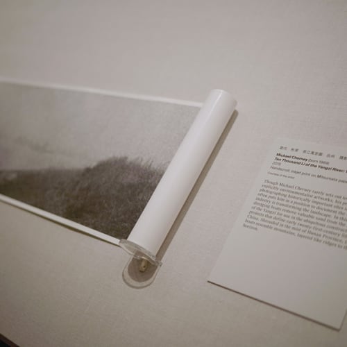 A scroll is a black and white photo, displayed in the museum, with a page of its description on the right