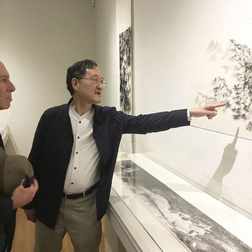 Anold Chang pointing at a piece of art