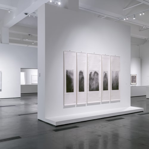 An exhibition space with five long scrolls hanging on the middle wall