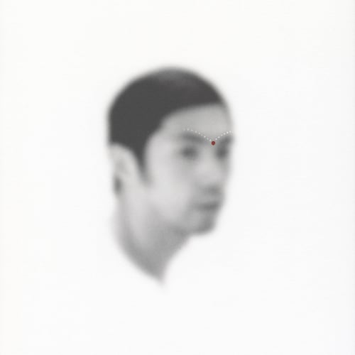 An out-of-focus portrait of a man with dots of acrylic paint on his brow