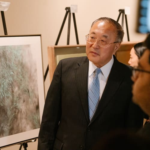 A person in a suit looking at a painting