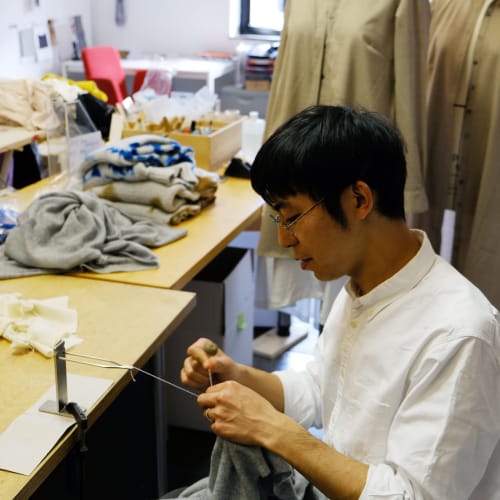Hiroyuki Murase sits in his work shop, sewing.