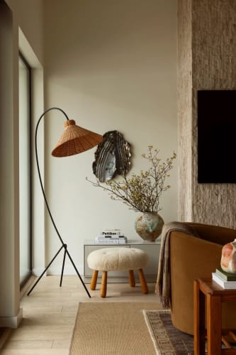 The living room features the L'Union arc lamp by Athena Calderone for Crate and Barrel, with a black lacquered iron base and rattan shade, and the glazed ceramic work Aftermath (10.19) by Brie Ruais, selected from the Albertz Benda gallery. Next to it, Jotham Hung's Lava Moon Jar from JF Chen and the Piano Key throw in wool and tussar silk by Pat McGann. A stool, inspired by Philip Arctander, adds a sculptural touch. Completing the scene is a console table from Meredith's New York apartment. Courtesy of Katie Salove Design Studio. Stylist by Lisa Rowe. Photographer by Sam Frost.