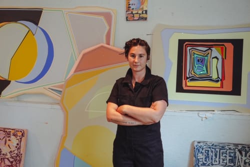 Jenna Pirello posing for picture in front of her paintings