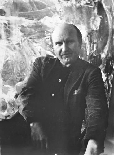 black and white photo of a man sitting in front of a painting