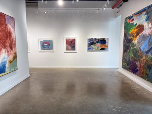 gallery with concrete floors and paintings on white walls