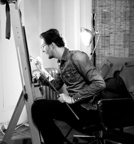 black and white photo of Zachary Oldenkamp drawing in his studio