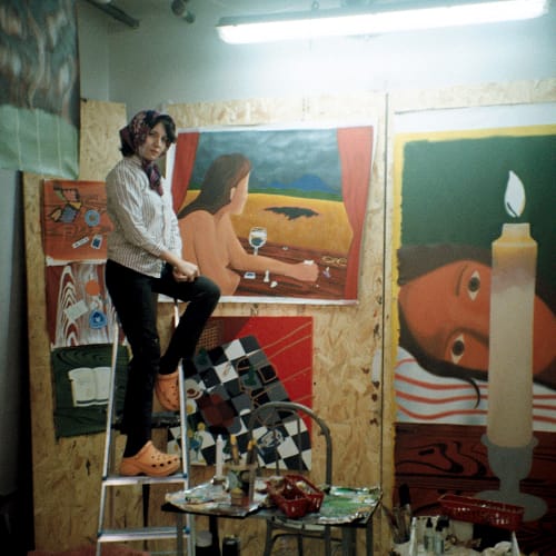 Image of Mexican artist Andrea Villalón on a ladder in front of her artwork