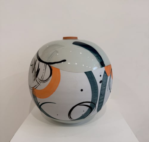 Ceramic vase with abstract design in orange, teal, and black on a white background.
