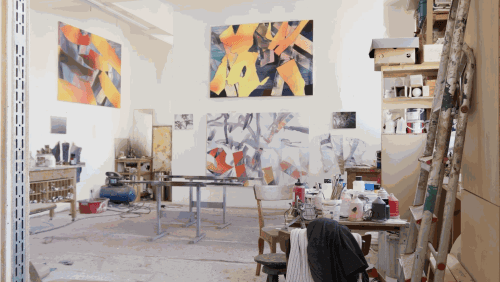 Vibrant paintings by Bernard Lokai on the walls in his utilitarian studio space.