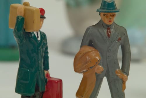 Two figurines in Liliana Porter's "The Riddle/ La Charada". One business man and one bell boy.