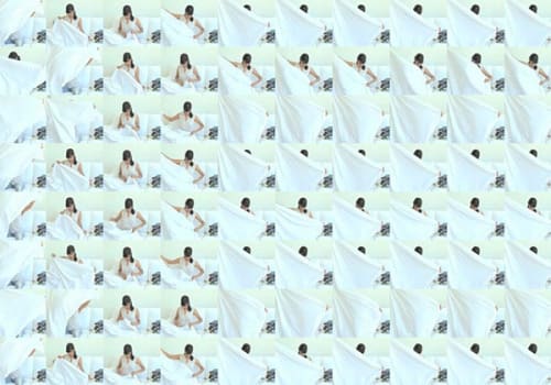 A grid of one woman folding a white sheet, at different times.