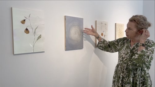 Marilla Palmer standing in front of a few of her paintings.