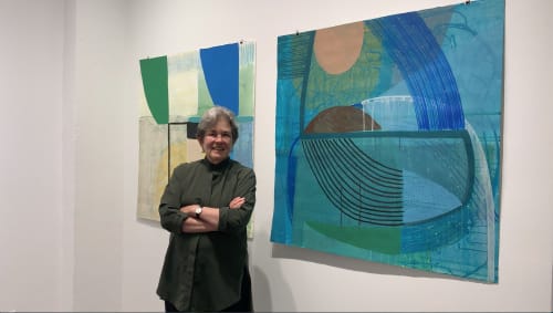 Woman standing in front of two abstract paintings on paper.