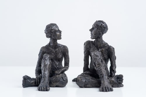 Carol Peace sculptures, a man and a woman, seated with their legs crossed mirroring each other, they look conversation. Highly textured and the iron resin is almost black.