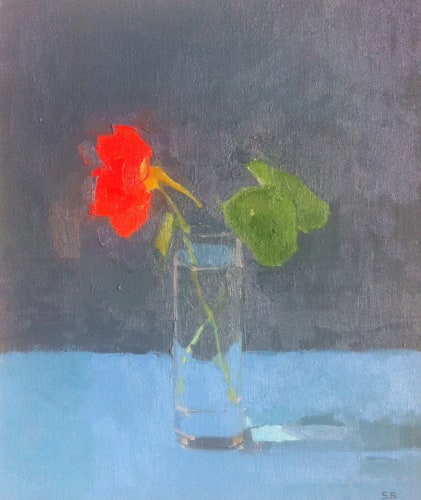 Sarah Spackman still life study of a luminous red single nasturtium in a tall glass, glowing against a purple toned grey background and a dusky blue surface.