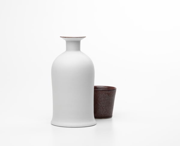 Kirsten Coelho Bottle and Cup, 2018 porcelain matt white glaze , iron oxide saturated iron glaze 2 Pieces: 20 cm H x 15 cm L x 15 cm W