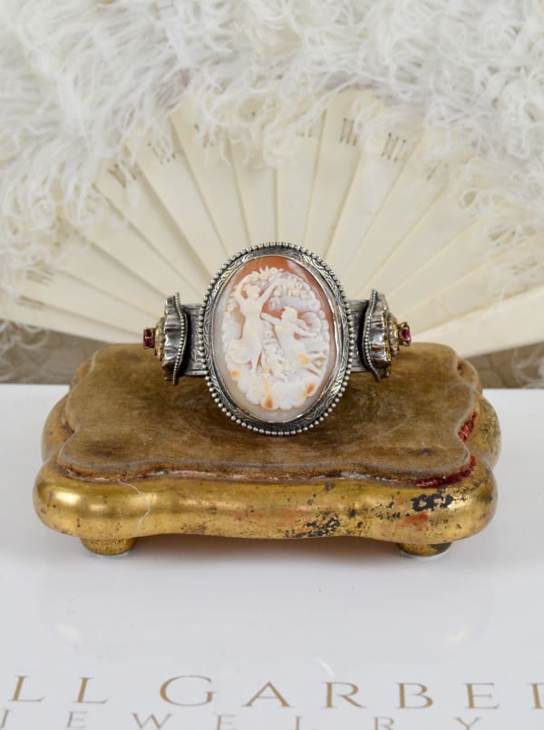 Jill Garber, A FINELY CARVED MUSEUM QUALITY - NINETEENTH CENTURY HARD SHELL CAMEO DEPICTING A VENETIAN GODDESS FROLICING WITH ANGELS ON A DISTINCTIVE FLORAL RELIEF EMBOSSED CUFF