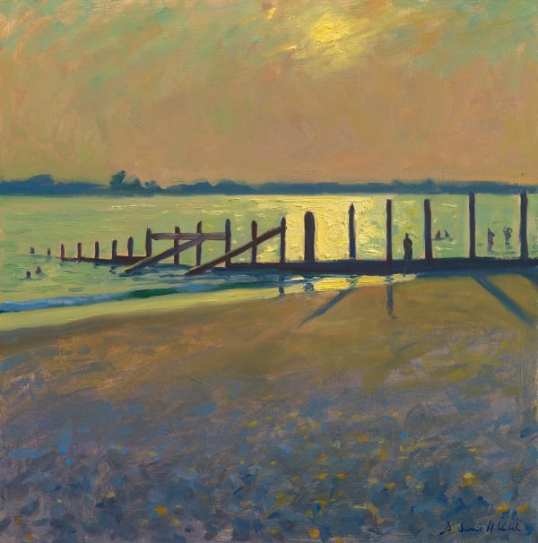 Long evening shadows and bright light on the water, sun setting at West Wittering