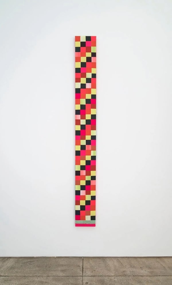 Tall, vertical textile piece. Diagonally alternating squares in black, pink, brown, yellow, orange, green, and red. Along the bottom are two stripes of pink and green.