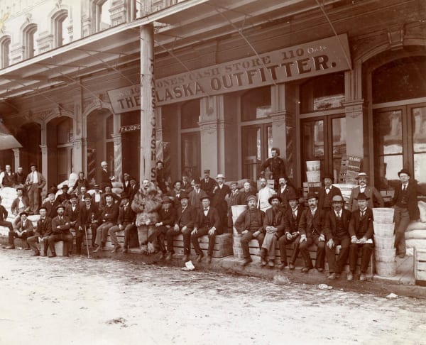 [Klondike Gold Rush], Group Portrait of Fortune-Seekers Posed in front of F.A. Jones "Alaska Outfitter" Cash Store in Portland, OR, 1890s
