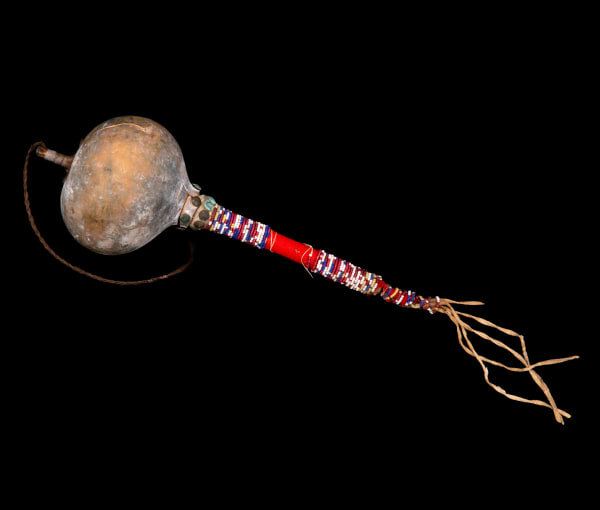 Lot 64 UNIDENTIFIED PLAINS ARTIST, POSSIBLY SIOUX Model Gourd Rattle with Beaded Handle, early 20th century gourd, wood, hide, glass beads, fabric, cotton string, brass tacks, pebbles, sinew, and hair, 11 x 4 x 4 in (27.9 x 10.2 x 10.2 cm) ESTIMATE: $150 — $250 PRICE REALIZED: $85.40