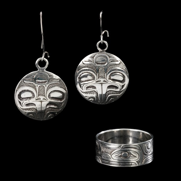 Lot 96 TIM BOYKO (1960-) HAIDA, SKIDEGATE, HAIDA GWAII & AN UNKNOWN ARTIST, PROBABLY HAIDA Ring & Earrings , c. 1990 / 1989 the ring: carved and engraved sterling silver, diameter 1.125 in (2.9 cm) / the earrings: carved an engraved sterling silver, each, diametre: 1 in (2.7 cm) ESTIMATE: $200 — $300 PRICE REALIZED: $168.00