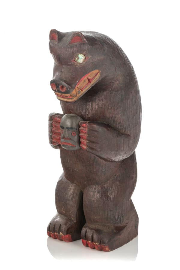 Lot 102 JIMMY JOHN (1876-1988), MOWACHAHT/MUCHALAHT (NUU-CHAH-NULTH) Bear Holding a Human Head, c. 1940s cedar, acrylic paint, and abalone, 9.75 x 4 x 4.75 in (24.8 x 10.2 x 12.1 cm) ESTIMATE: $400 — $600 PRICE REALIZED: $480.00