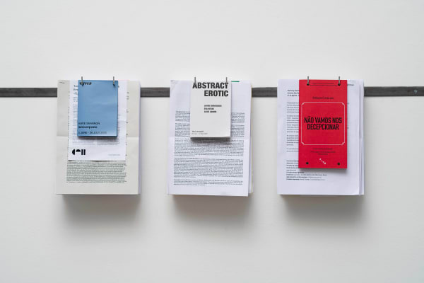 Ilê Sartuzi Trabalho (Abril-Outubro) [Work (April-October)], 2025 gancho de aço inoxidável e impressos de exposições [stainless steel hook and exhibition printed materials] 30.5 x 80 x 10 cm 12 x 31 ½ x 4 in