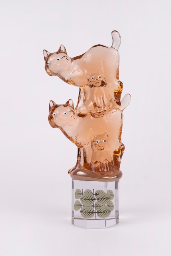 Rasmus Nossbring glasskulptur med fyra rosa katter med ögon. balanserade på en hexagonformad klack i glas med berså dekal.