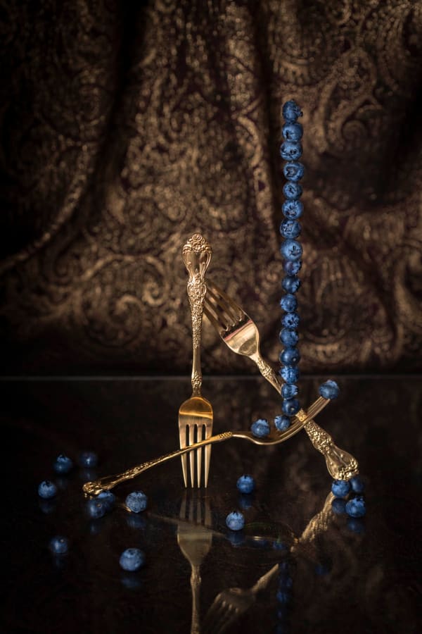 berries stacked on balanced gold forks photo