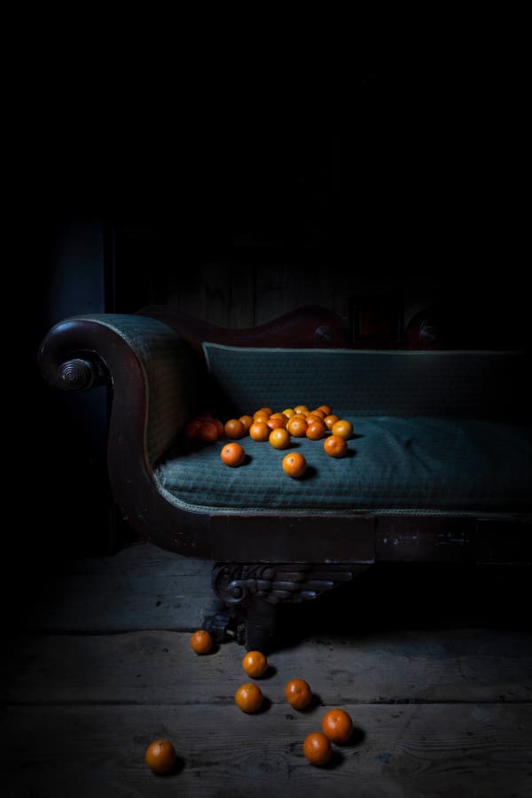 oranges on couch and floor in dark room photo by jp terlizzi